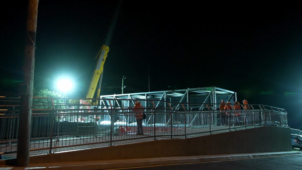 Frederick Street Footbridge under construction at night with crane installing bridge.